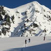 Skiers head up the flat portion of the ridge below Peak 8100. The route continues up the prominent ridge behind them.